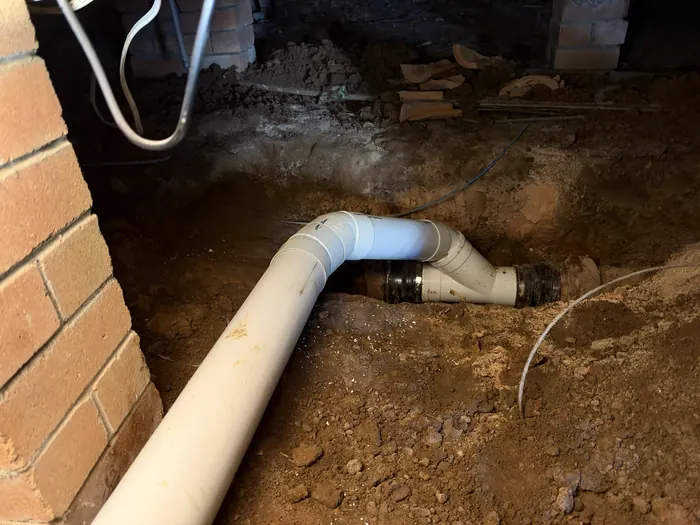 Rubber coupling joining the new PVC sewer to the old clay line under the house, Mount Pritchard